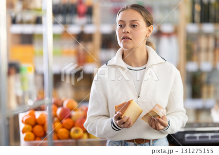 Choose cheese in supermarket - woman chooses what cheese to buy in the dairy department section of store Choose cheese in supermarket - woman chooses what cheese to buy in the dairy department section of store 131275155