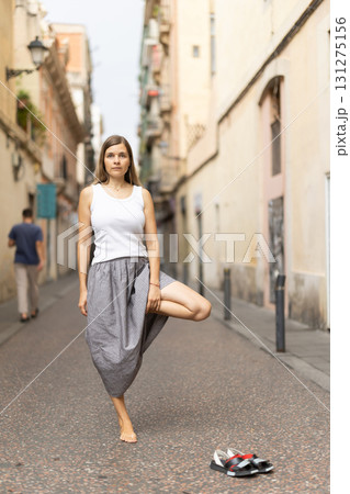 Woman in midst of bustle of city in pose of tree asana Woman in midst of bustle of city in pose of tree asana 131275156