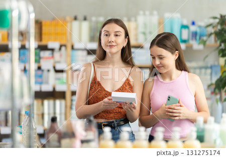 young woman with her daughter choosing pills at the pharmacy 131275174
