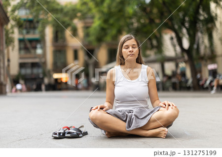 Woman in midst of bustle of city in pose of lotus asana Woman in midst of bustle of city in pose of lotus asana 131275199