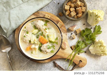 Hearty meatball soup with vegetables and herbs for a cozy meal. 131275208