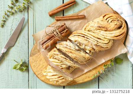 Braided cinnamon sweet bread on rustic wooden board with cinnamon sticks and herbs. Braided cinnamon sweet bread on rustic wooden board with cinnamon sticks and herbs. 131275218
