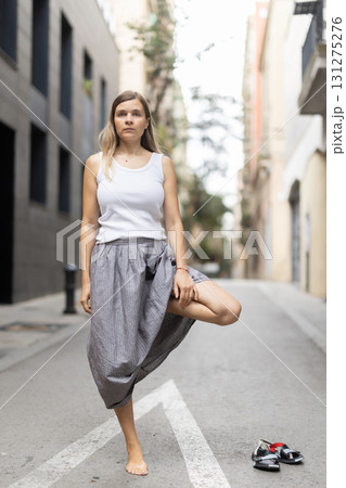 Woman in midst of bustle of city in pose of tree asana Woman in midst of bustle of city in pose of tree asana 131275276