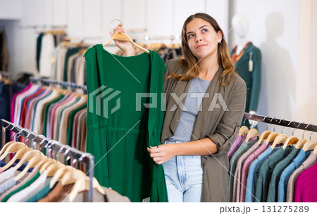 Young woman choosing knitted vest in store 131275289