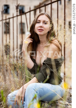 Young sexy woman posing near an abandoned building near wrought iron fence 131275378