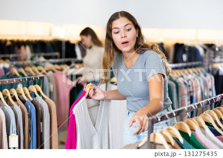 Young woman choosing knitted sweater in store 131275435