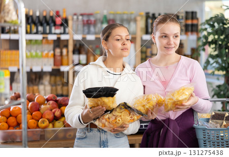 Young women choosing chips in grocery store 131275438