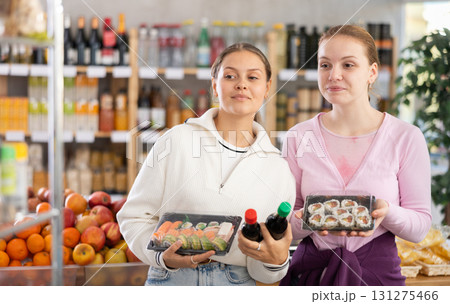 Young women choose sushi and sauces for them Young women choose sushi and sauces for them 131275466