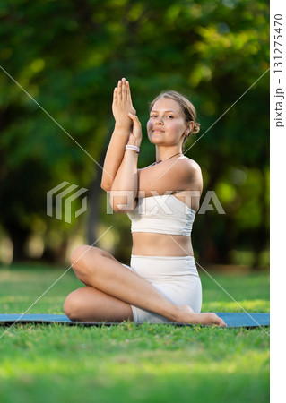 Girl doing Gomukhasana Garudasana yoga pose in summer park Girl doing Gomukhasana Garudasana yoga pose in summer park 131275470