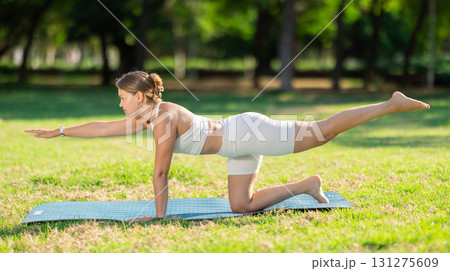 Girl in park on green grass of lawn performs Dandayama Bharmansana Girl in park on green grass of lawn performs Dandayama Bharmansana 131275609