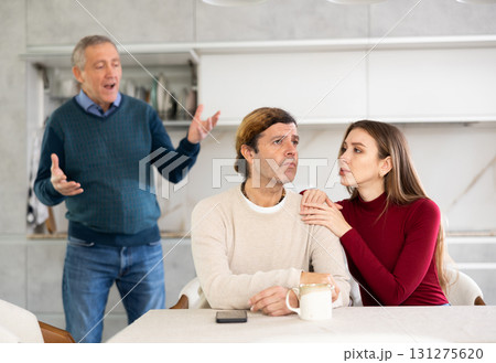 Elderly father scolds and shouts at a married couple. Quarrel in home kitchen Elderly father scolds and shouts at a married couple. Quarrel in home kitchen 131275620
