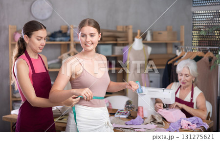 adult female dressmaker takes measurements for a client in the workshop 131275621
