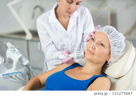 Young female cosmetologist doing whitening procedure to adult woman 131275667