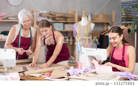 Woman tailor sewing, senior and young employee assistant drawing paper dress pattern by curves 131275803