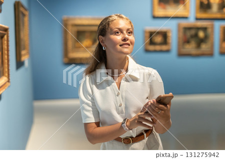 Woman with phone in hands view pictures and icons in museum hall Woman with phone in hands view pictures and icons in museum hall 131275942