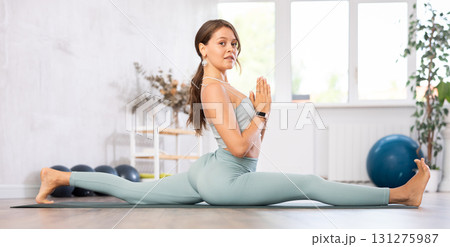 Young athletic woman doing splits while practicing yoga Young athletic woman doing splits while practicing yoga 131275987