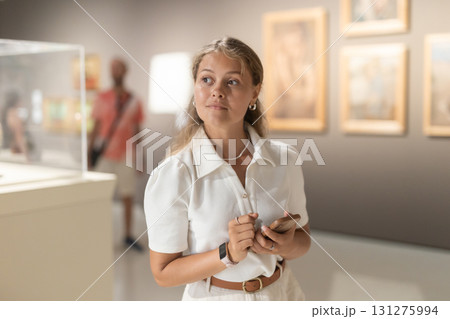 Girl with phone in hands walks around museum hall, view exhibition items 131275994