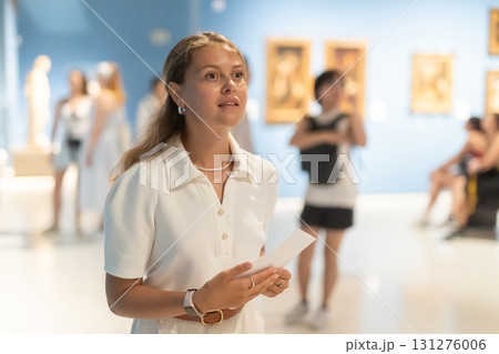 Woman with sheet piece of paper in hands view pictures and icons in museum hall 131276006