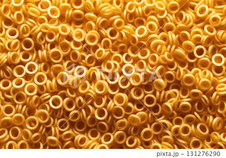 Dive into the whimsical world of pasta with this mesmerizing close-up shot of golden ring-shaped pasta. 131276290