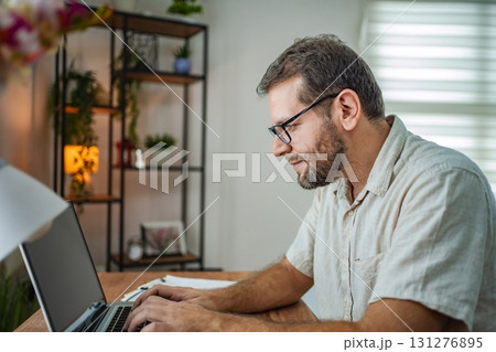 Focused man working on his laptop in a cozy workspace Focused man working on his laptop in a cozy workspace 131276895