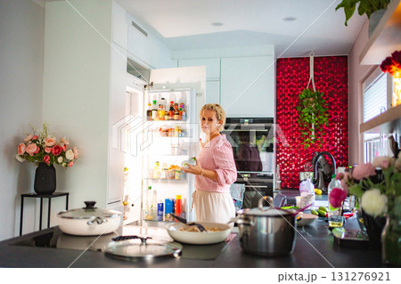 Woman taking food from refrigerator in modern kitchen Woman taking food from refrigerator in modern kitchen 131276921