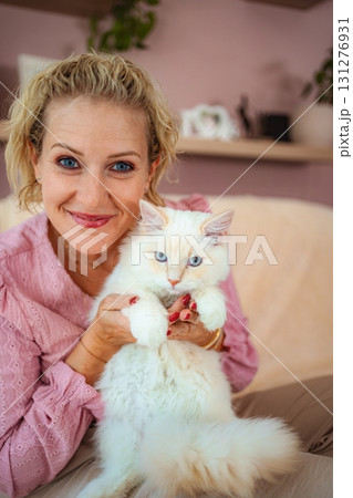 Woman smiling holding fluffy white cat with blue eyes Woman smiling holding fluffy white cat with blue eyes 131276931