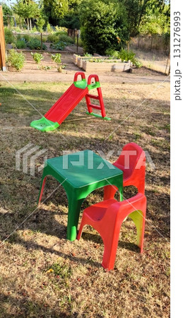 Children's corner at the dacha: a bright table, chairs and a slide on green grass 131276993