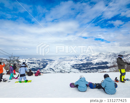 スキー場の山頂で絶景を眺めながら滑走準備をするスノーボーダーたち (新潟県、南魚沼市、石打丸山) 131277425