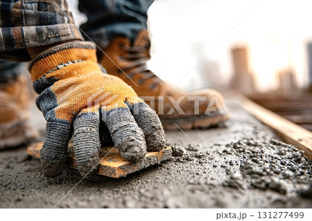 Construction worker leveling concrete surface with wooden float 131277499