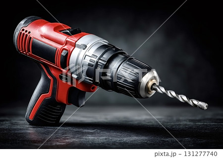 Red and black cordless drill resting on dark background 131277740