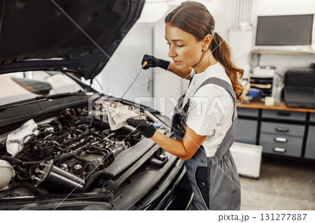 A confident female mechanic diligently performing car maintenance with great expertise 131277887