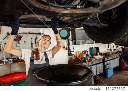An Automotive Mechanic Engaged in Essential Work While Under a Vehicle in a Garage Workspace An Automotive Mechanic Engaged in Essential Work While Under a Vehicle in a Garage Workspace 131277897