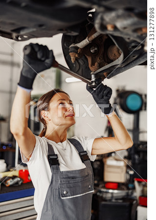 A woman is engaged in auto maintenance work in a wellequipped garage, showcasing her skills A woman is engaged in auto maintenance work in a wellequipped garage, showcasing her skills 131277898