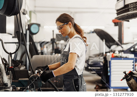 A skilled female mechanic diligently working in an automotive garage environment 131277910