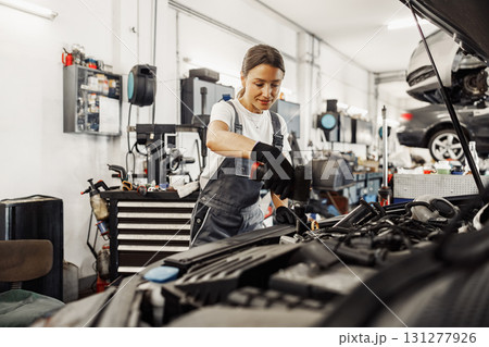 A female mechanic diligently working on a car in a modern and wellequipped auto shop setting 131277926