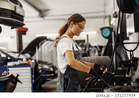 Female mechanic diligently working in an automotive shop, showcasing her skills and craftsmanship 131277934