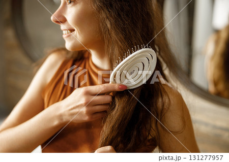 A Woman Brushing Her Long Hair with a Spiral Brush in a Cozy and Inviting Setting 131277957