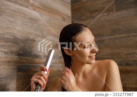 A woman is styling her hair in the shower using a flat iron to achieve a chic look A woman is styling her hair in the shower using a flat iron to achieve a chic look 131277987