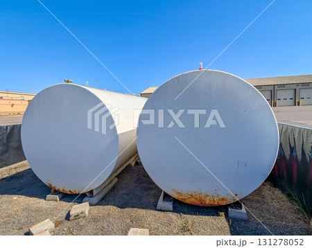 Large industrial storage tanks placed side by side in an outdoor facility under clear blue sky during daytime hours 131278052