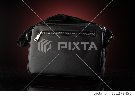 This black bag mockup showcases a sleek design featuring a prominent zipper pocket. The dark red background enhances its stylish appearance ideal for advertising or design presentations. This black bag mockup showcases a sleek design featuring a prominent zipper pocket. The dark red background enhances its stylish appearance ideal for advertising or design presentations. 131278459