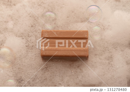 bar of soap sits on a surface covered with gentle bubbles creating a soothing atmosphere for a relaxing bath experience. The light reflects softly off the bubbles enhancing the calming effect. bar of soap sits on a surface covered with gentle bubbles creating a soothing atmosphere for a relaxing bath experience. The light reflects softly off the bubbles enhancing the calming effect. 131278480