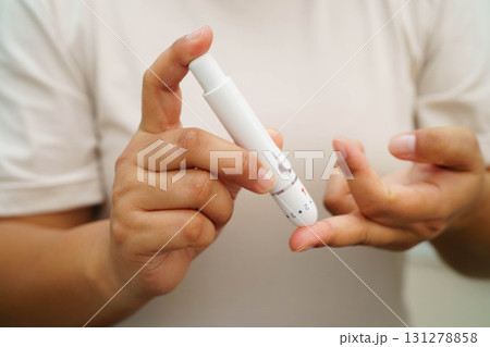 Asian woman self testing to check blood sugar level diabetes by digital lancet on finger at home. 131278858