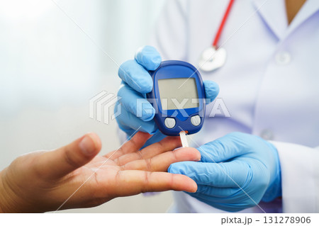 Asian doctor using digital glucose meter for check sample blood sugar level to treatment diabetes. Asian doctor using digital glucose meter for check sample blood sugar level to treatment diabetes. 131278906