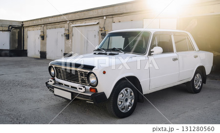 next to the body shop stands a classic white four-door sedan from the 1970s 131280560