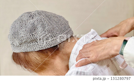 高齢女性の肩を後ろからもむ女性の手_横から 131280797