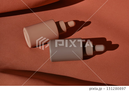 Two bottles of facial serum on a terracotta background. 131280897