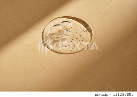 A drop of serum on a beige background. 131280899