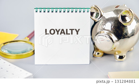 LOYALTY word written in a notebook in a composition with a piggy bank and a magnifying glass. Fake Dictionary, Dictionary definition concept. LOYALTY word written in a notebook in a composition with a piggy bank and a magnifying glass. Fake Dictionary, Dictionary definition concept. 131284881