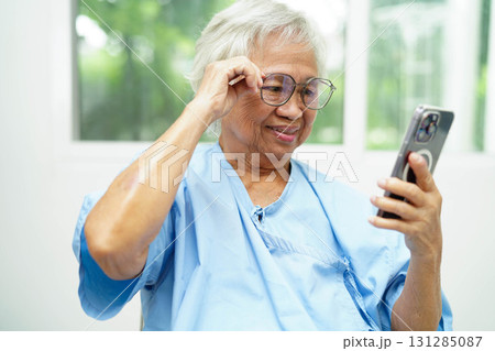 Asian senior woman wearing eyeglasses or vision glasses using a smartphone at home care service. Asian senior woman wearing eyeglasses or vision glasses using a smartphone at home care service. 131285087