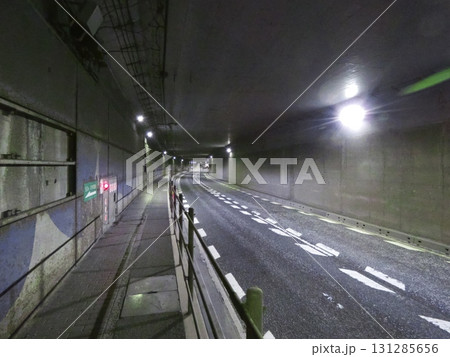 夜間の地下道・トンネル。湾曲する道路と誘導灯、無機質な壁 夜間の地下道・トンネル。湾曲する道路と誘導灯、無機質な壁 131285656